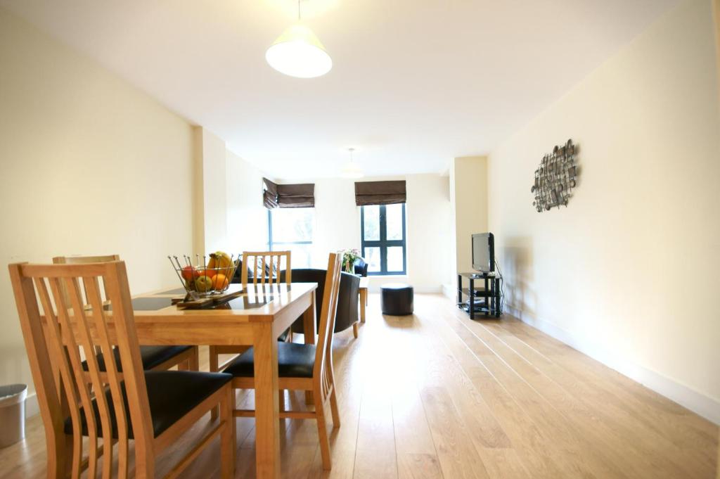 a dining room and living room with a table and chairs at Lodge Drive Serviced Apartments in Enfield