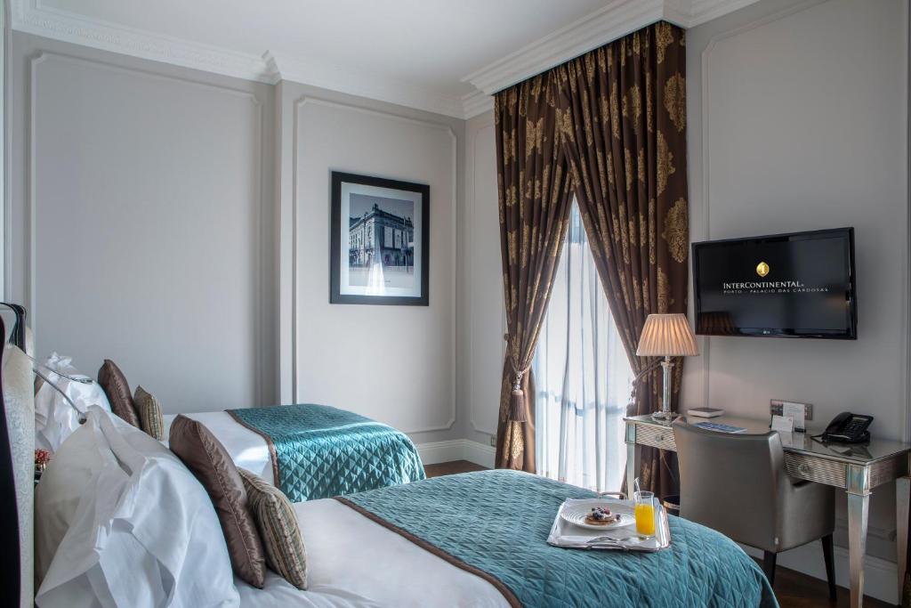 a hotel room with a bed and a desk and a television at InterContinental Porto - Palacio das Cardosas by IHG in Porto