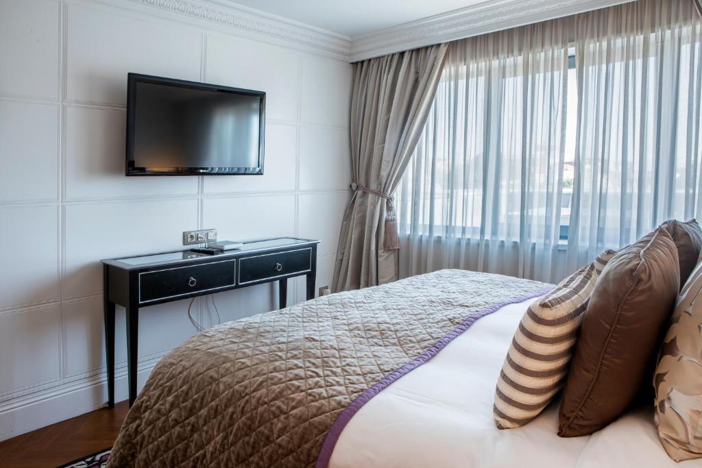 a bedroom with a bed with a television on the wall at InterContinental Porto - Palacio das Cardosas by IHG in Porto