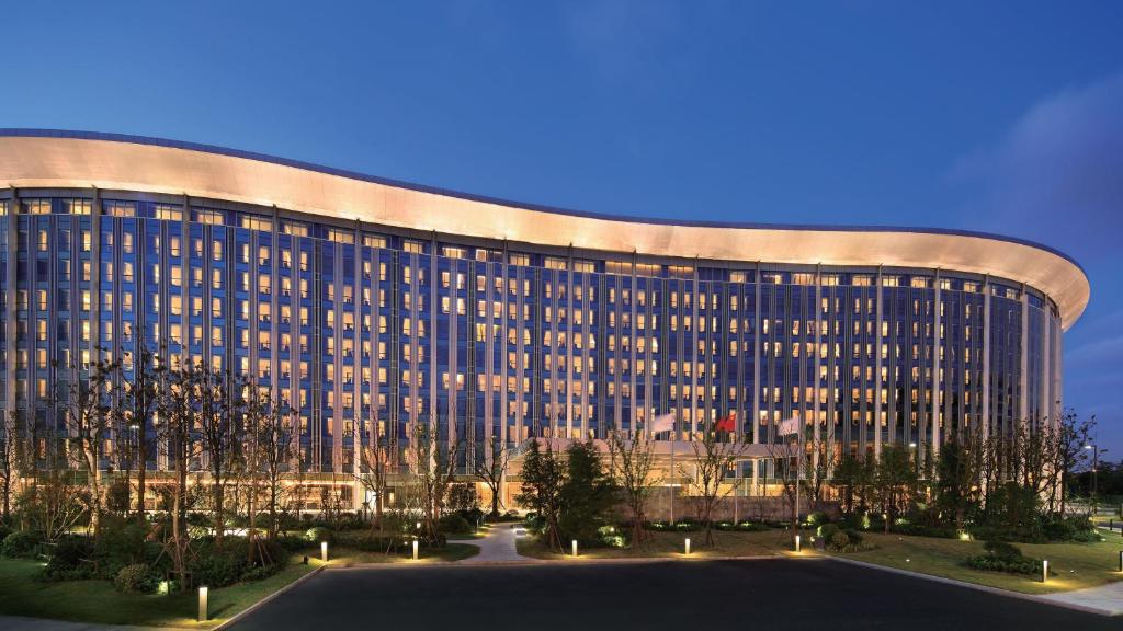 a large building with a curved facade at night at InterContinental Shanghai Hongqiao NECC, an IHG Hotel in Shanghai