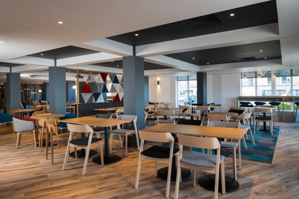 a restaurant with wooden tables and chairs at Holiday Inn Express Edinburgh - Leith Waterfront by IHG in Edinburgh