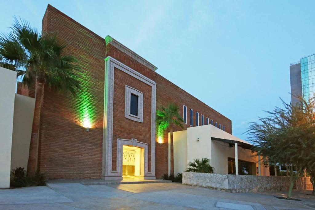 un edificio de ladrillo con puerta y palmeras en Holiday Inn Hermosillo, an IHG Hotel, en Hermosillo