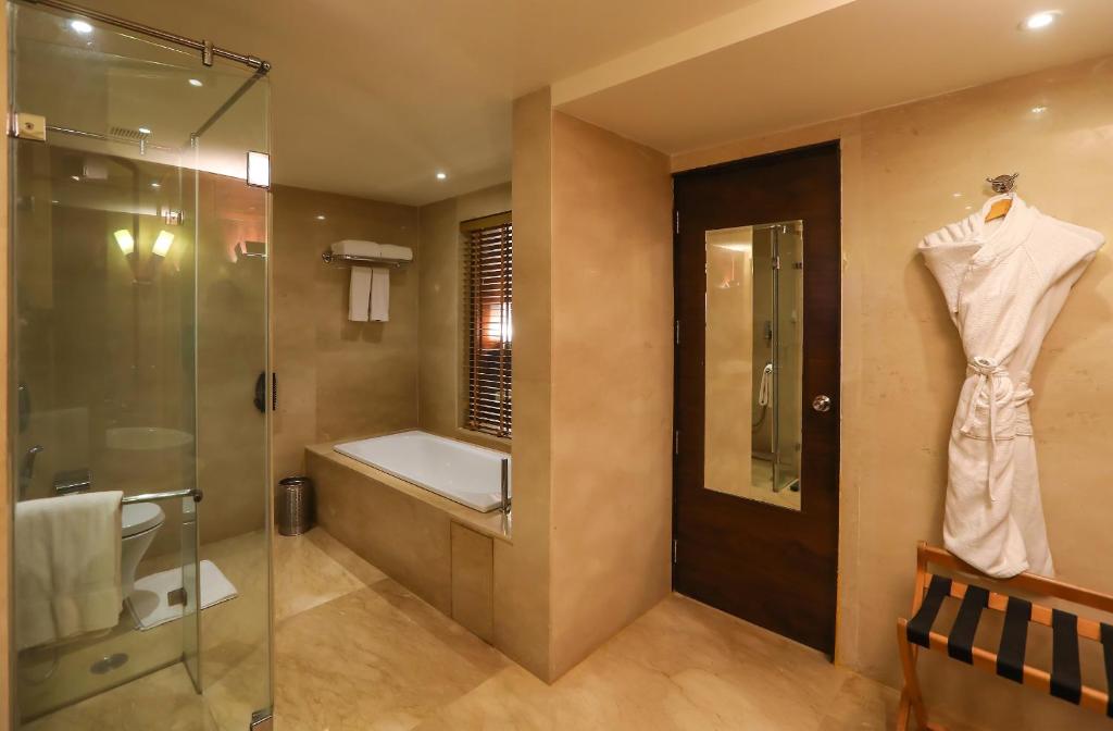 a bathroom with a tub, toilet, sink and shower at Radisson Blu Hotel Chennai City Centre in Chennai