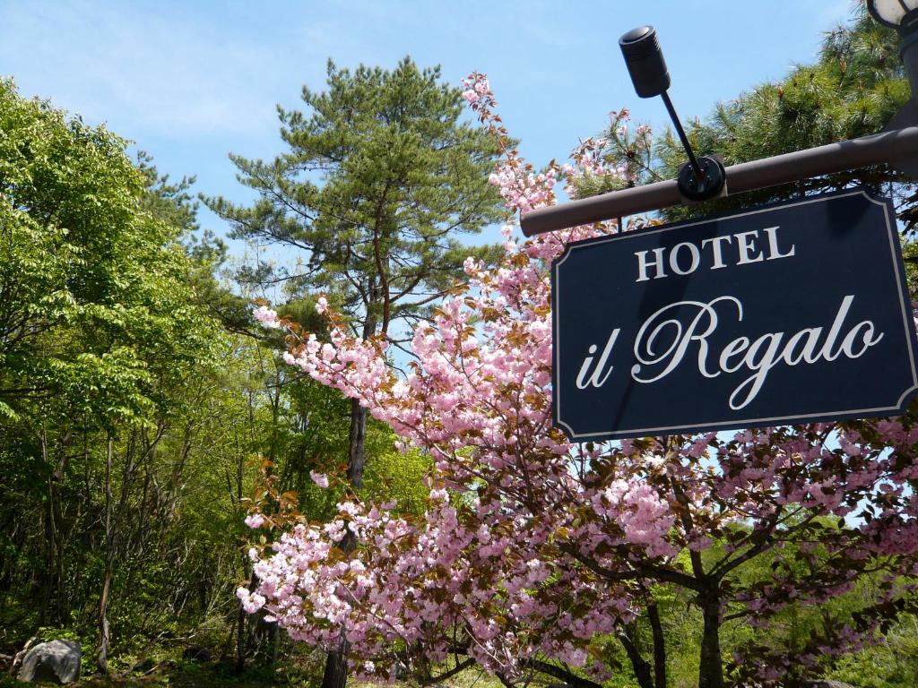 un panneau indiquant un hôtel qu'il reporia devant un arbre à fleurs dans l'établissement il Regalo イルレガーロ, à Kitashiobara