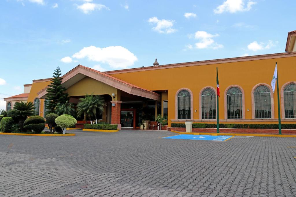 ein gelbes Gebäude mit Flaggen davor in der Unterkunft Holiday Inn La Piedad, an IHG Hotel in La Piedad Cavadas