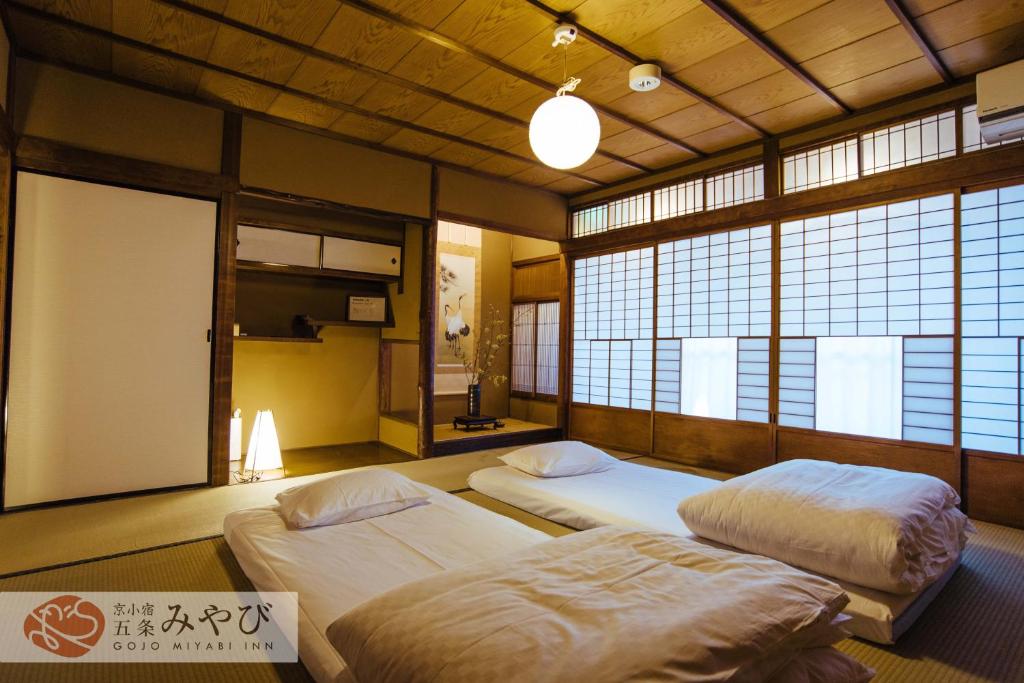 2 camas en una habitación con ventanas en Gojo Miyabi Inn, en Kioto