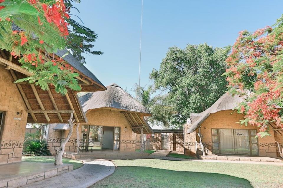 una casa con techo de paja y patio en Tshukudiba Game Lodge en Tom Burke