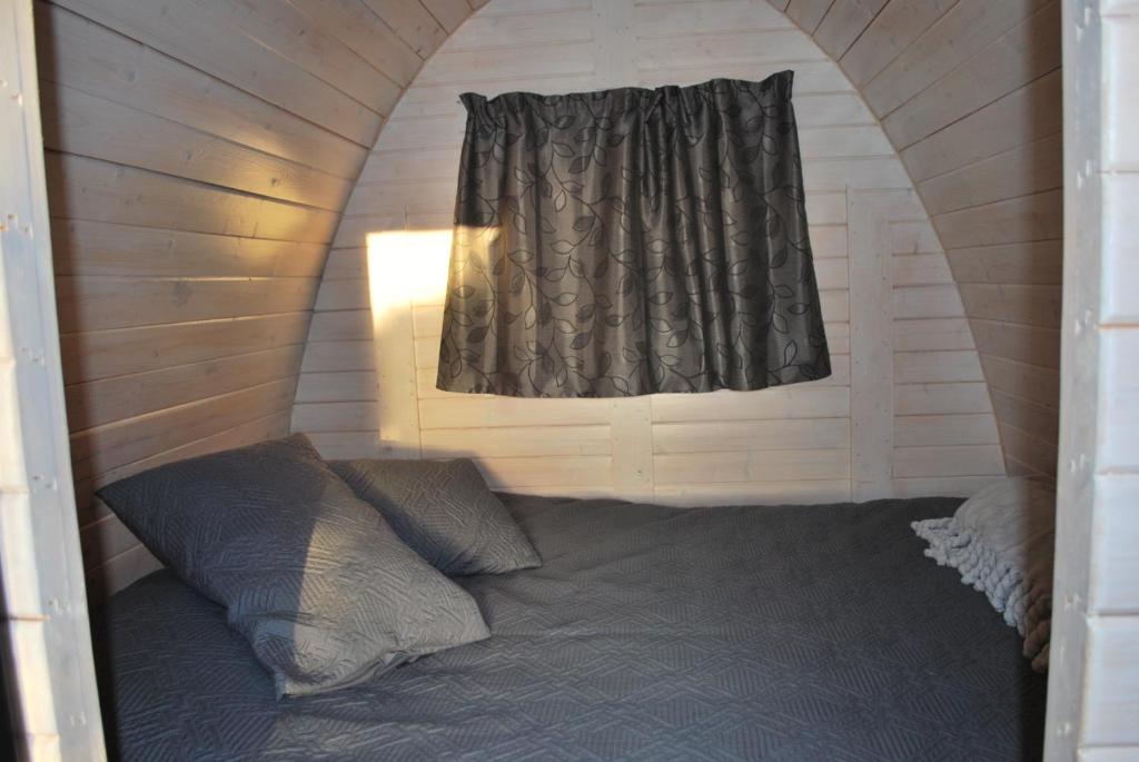 Łóżko w małym pokoju z oknem w obiekcie River & Trail Camping Pod w mieście Hokitika