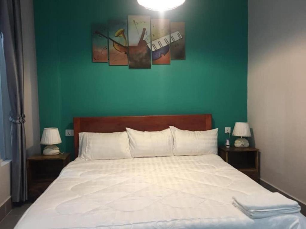 a bedroom with a white bed with a green wall at Mean Leap Guesthouse in Kampot