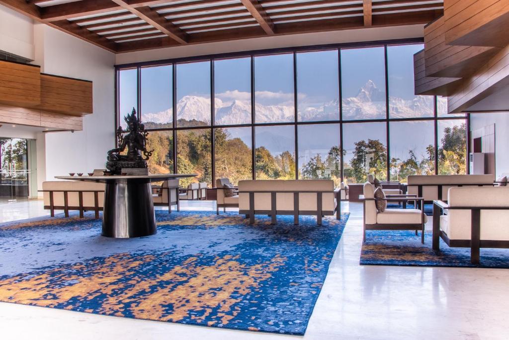uma grande sala com mesas e cadeiras e grandes janelas em Hotel Annapurna View Sarangkot em Pokhara