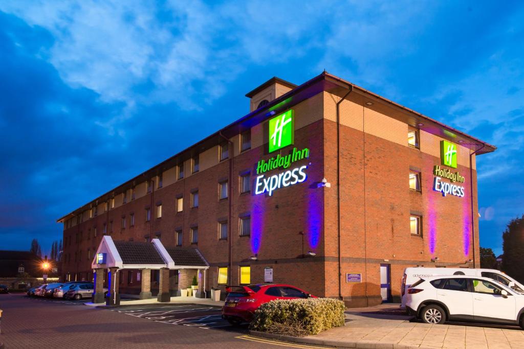 Holiday Inn Express Birmingham Oldbury, an IHG Hotel في أولدبيري: فندق به لافتات نيون على جانب مبنى