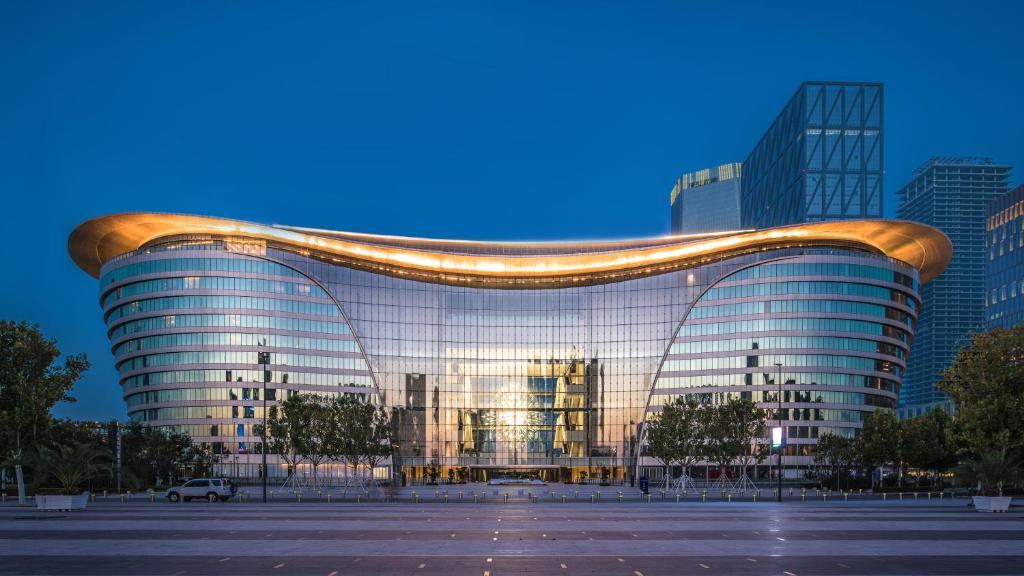 a large glass building in a city at night at InterContinental Tianjin Yujiapu Hotel & Residences, an IHG Hotel in Binhai