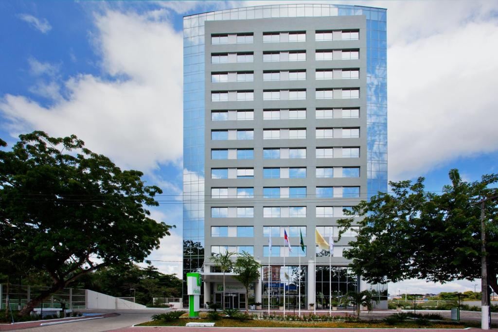 um edifício de escritórios alto e azul com árvores em frente em Holiday Inn Manaus, an IHG Hotel em Manaus