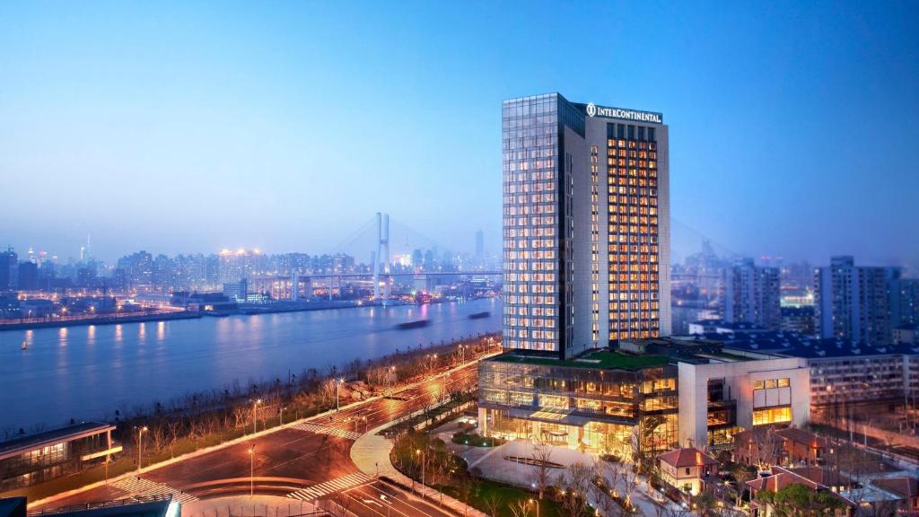 上海市にあるインターコンチネンタル 上海 エクスポの都市の川の横の高層ビル