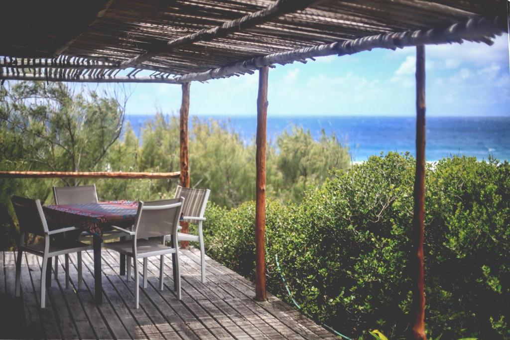 a patio with a table and chairs and the ocean at Tofinho Beach House in Praia do Tofo