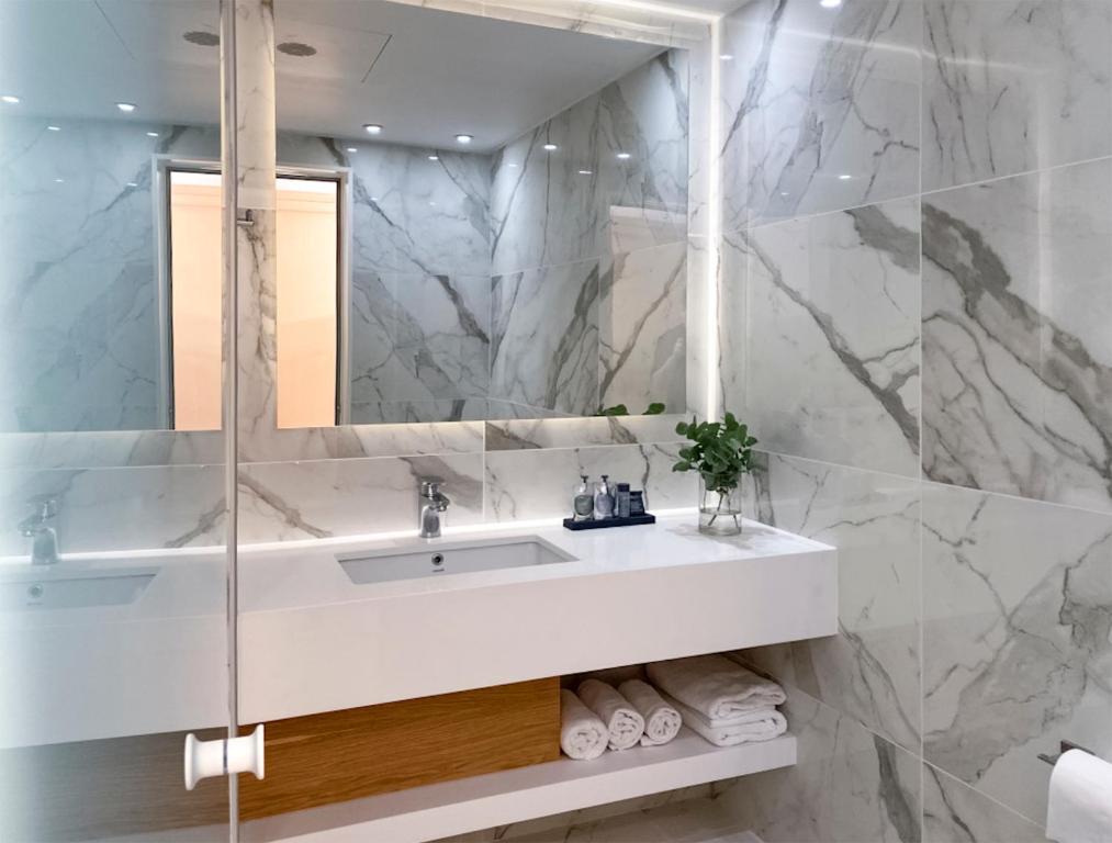 a white bathroom with a sink and a mirror at Ajax Hotel in Limassol