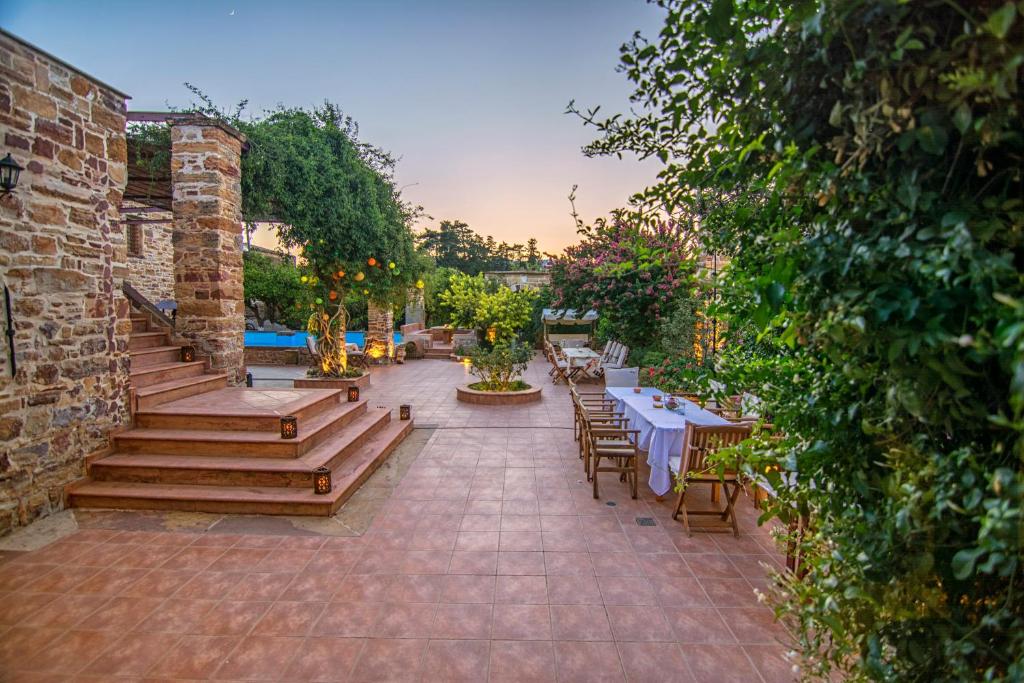 un patio al aire libre con mesas y sillas y una piscina en Mouzaliko Guesthouse Mansion, en Kambos