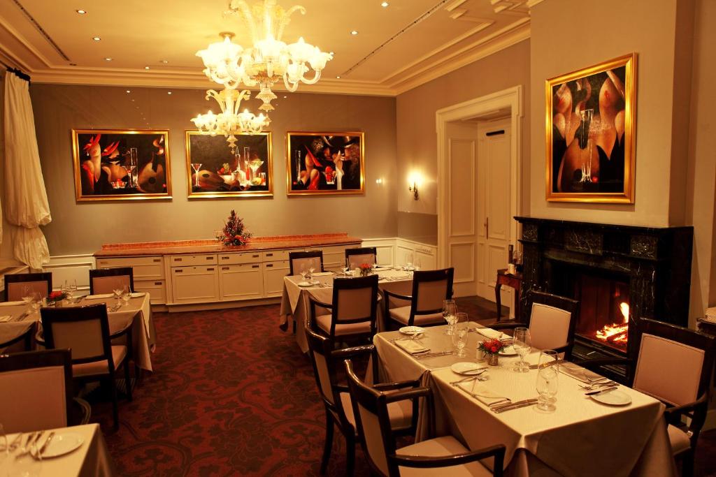 a dining room with tables and chairs and a fireplace at Le Palais Art Hotel Prague in Prague