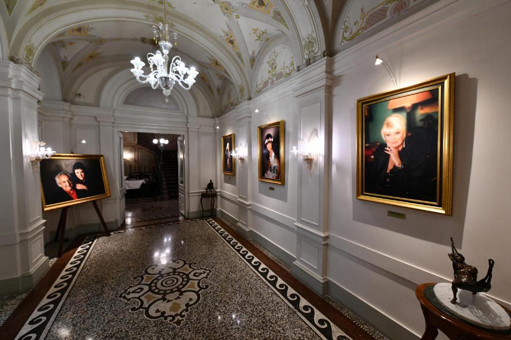 a hallway with paintings on the walls and a chandelier at Le Palais Art Hotel Prague in Prague