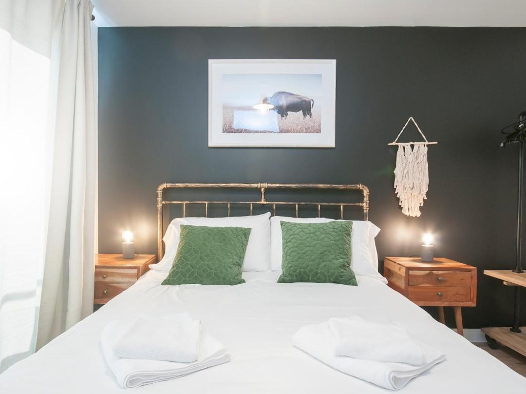 a bedroom with a large white bed with green pillows at New modern Apt in the City & close to Stadiums in Cardiff