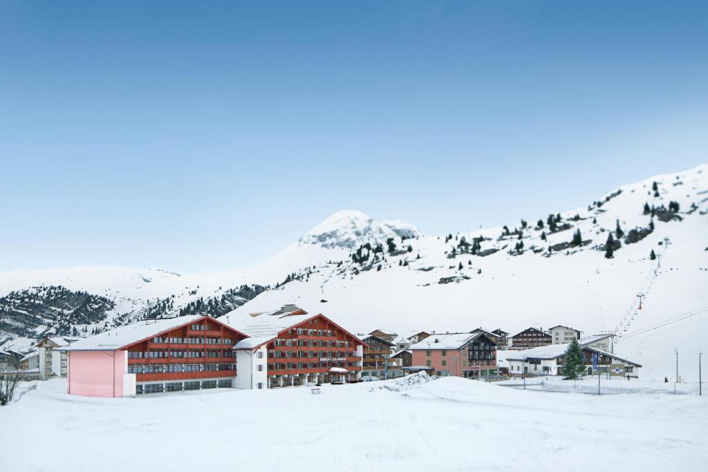 un grupo de edificios en una montaña cubierta de nieve en ROBINSON ALPENROSE Zürs, en Zürs am Arlberg