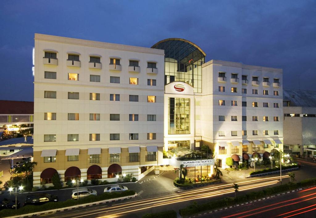 a large white building with cars parked in front of it at Surabaya Suites Hotel Powered by Archipelago in Surabaya