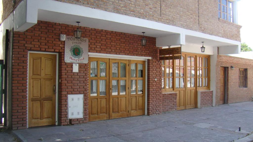 un edificio de ladrillo con puertas y ventanas de madera en Hostería Gwesty Plas y Coed en Gaiman