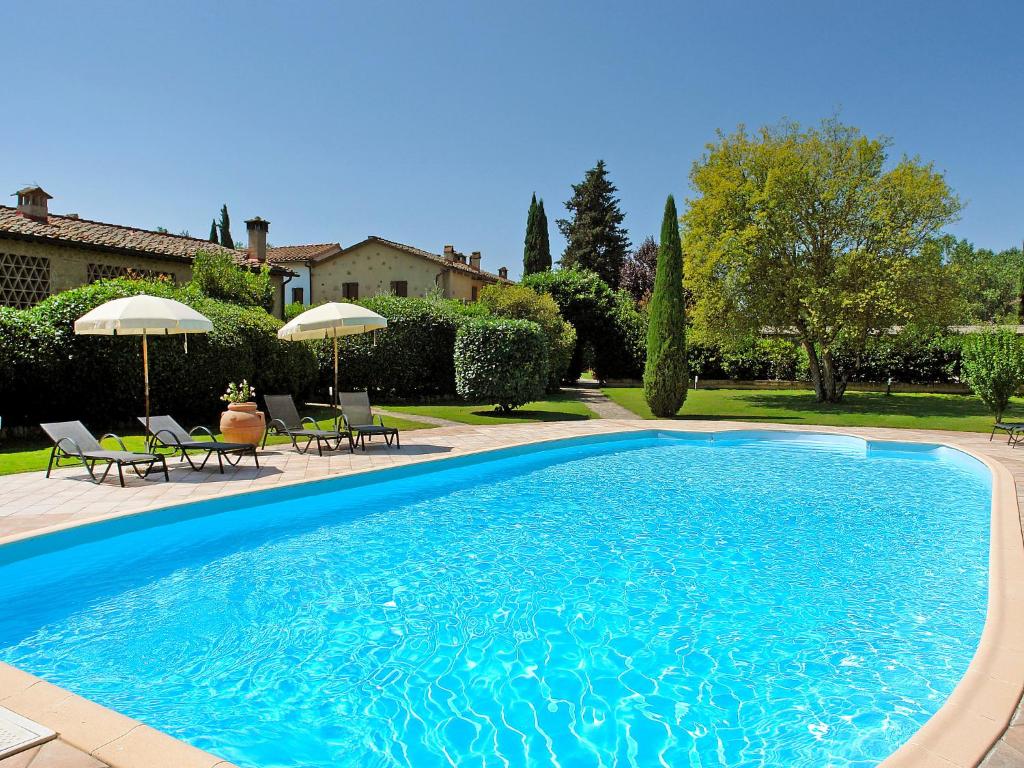 een zwembad met stoelen en parasols in een tuin bij Holiday Home Capanna di Sopra by Interhome in Villa Bertolli