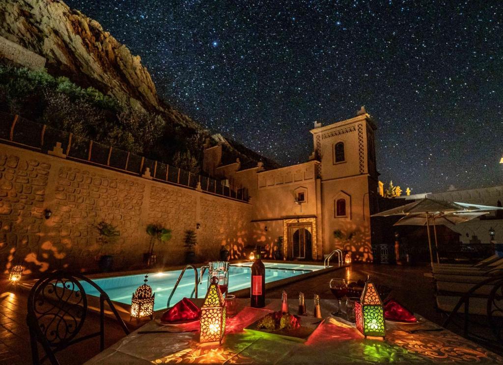 a building with a pool and a church at night at Hotel Riad Bahammou in Aït Idaïr