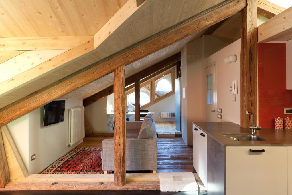 una cocina con un loft con techos de madera en Mansarda in Centro en Fiera di Primiero