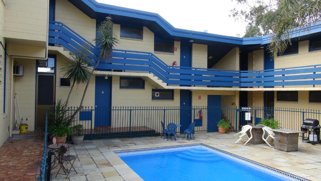 a swimming pool in front of a building with blue stairs at Pathfinder Motel in Melbourne