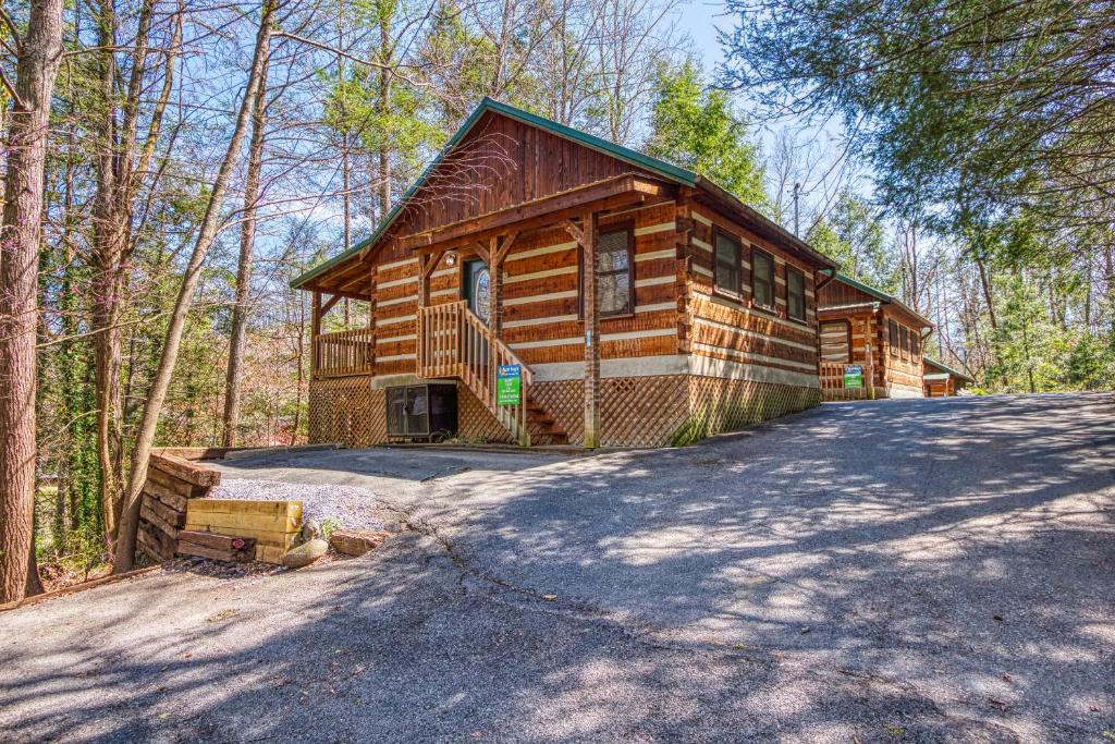 a log cabin in the woods with a driveway at Puppy Love #1619 in Gatlinburg