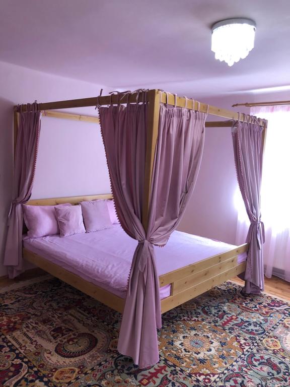 a bedroom with a canopy bed with purple curtains at Casa Weiss in Sibiu