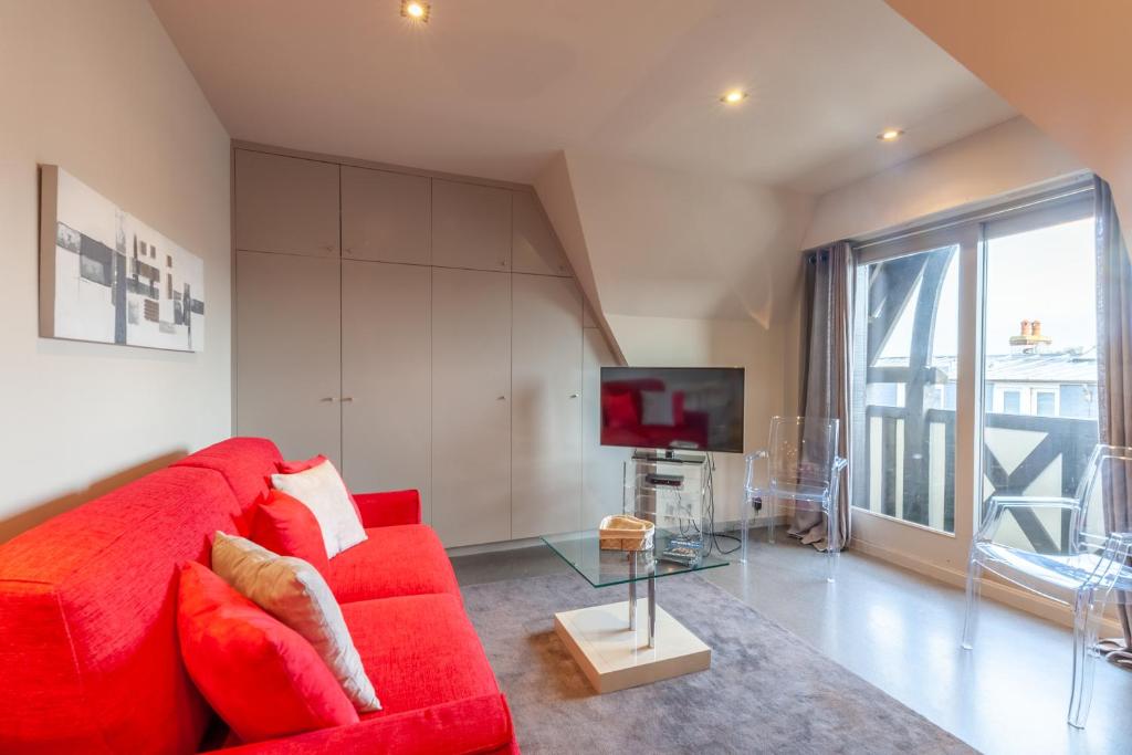 een woonkamer met een rode bank en een tv bij CMG Place Morny/ Deauville in Deauville