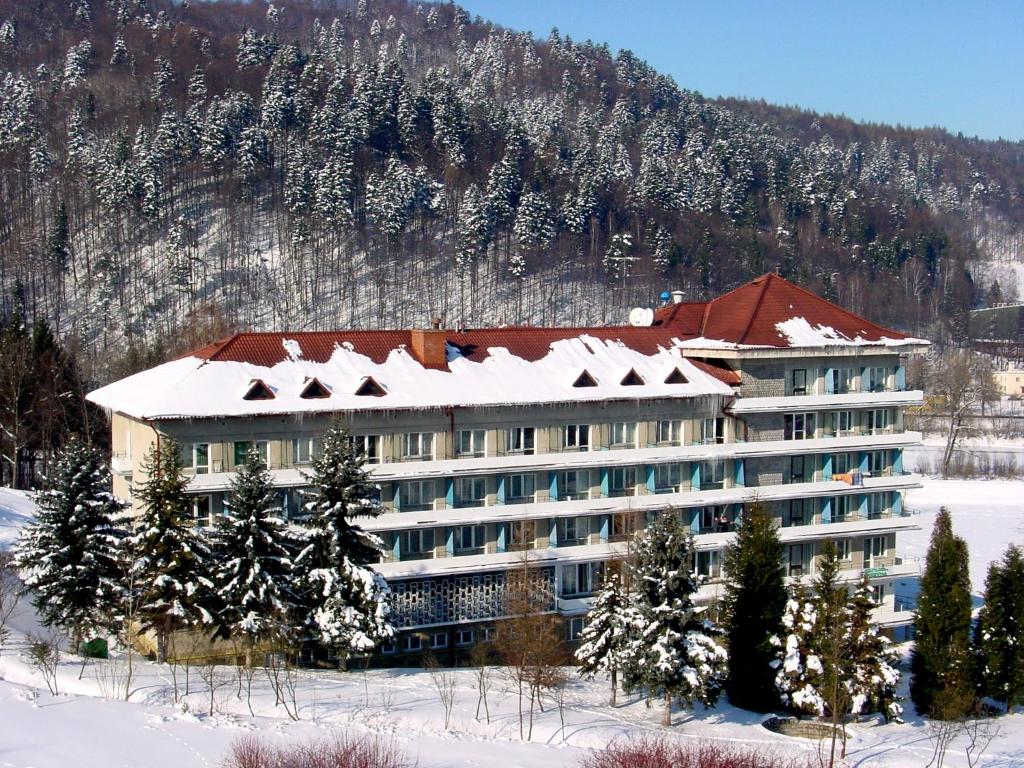 a hotel in the snow in front of a mountain at Uzdrowisko Muszyna nad Popradem in Muszyna