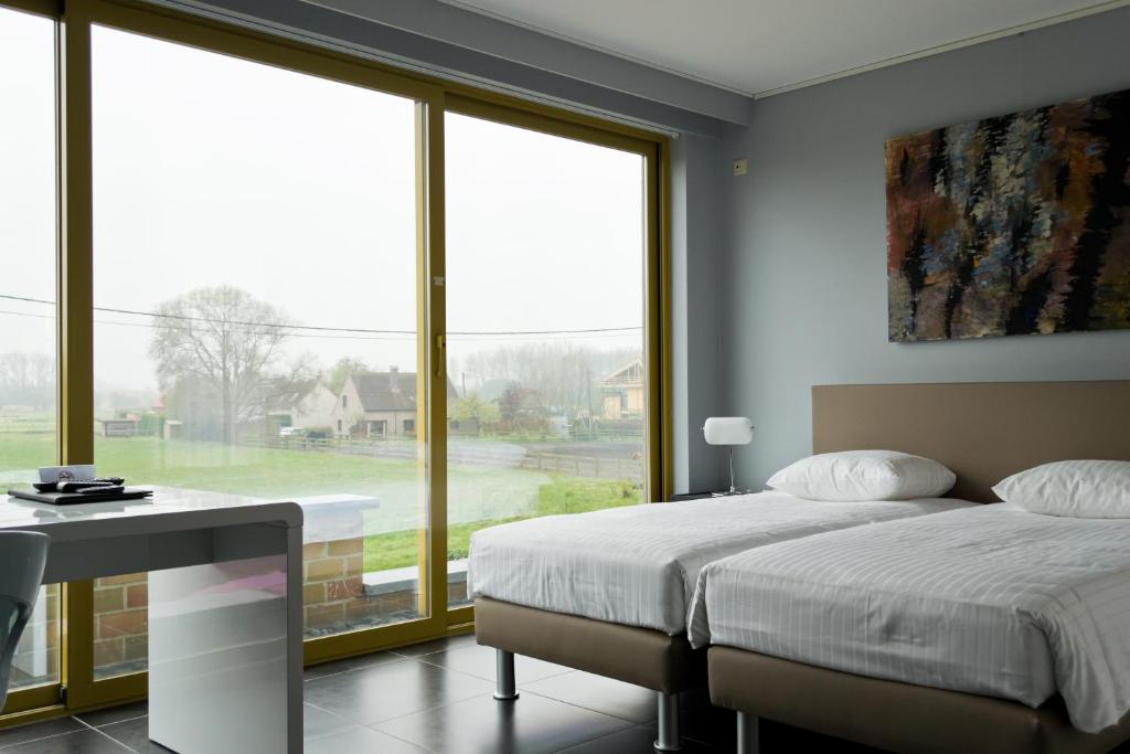 Hotel Essenza في Puurs: غرفة نوم بسريرين ونافذة كبيرة