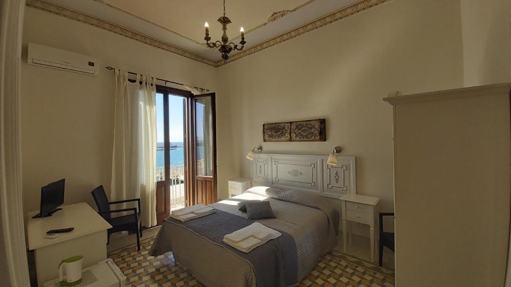 a bedroom with a bed and a desk and a window at B&B Belveliero - Il Capitano in Trapani