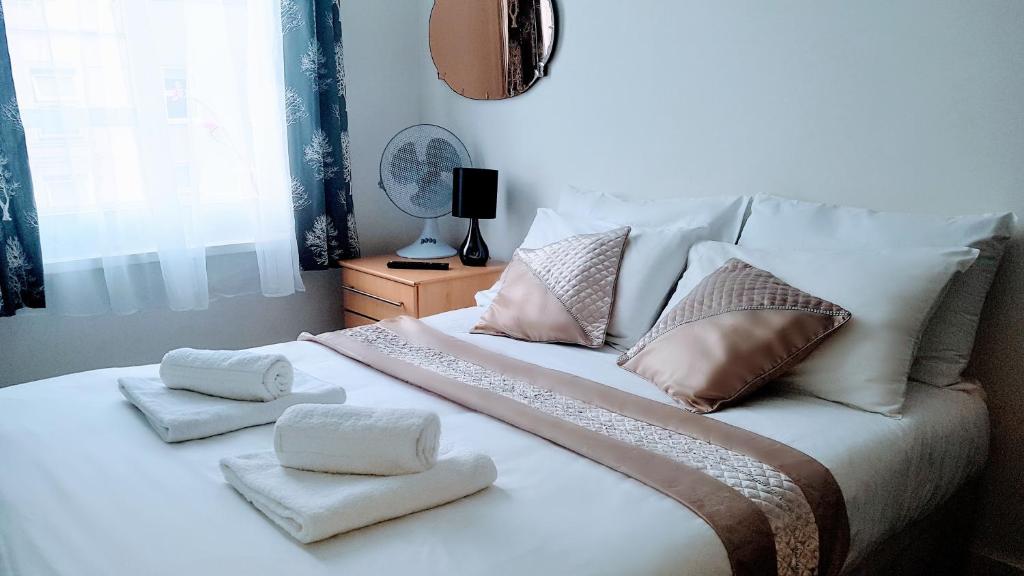un letto bianco con asciugamani e cuscini sopra di Central Comfort Rooms a Londra