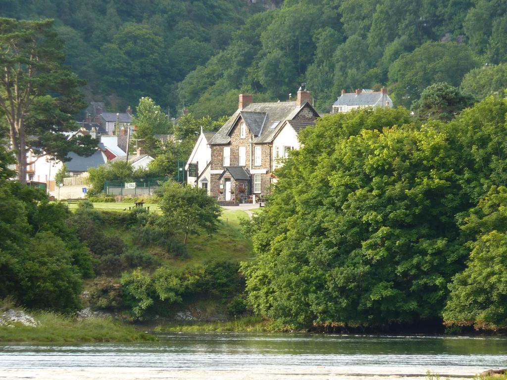 a house with trees and houses on the side of the river at Teifi Netpool in Cardigan
