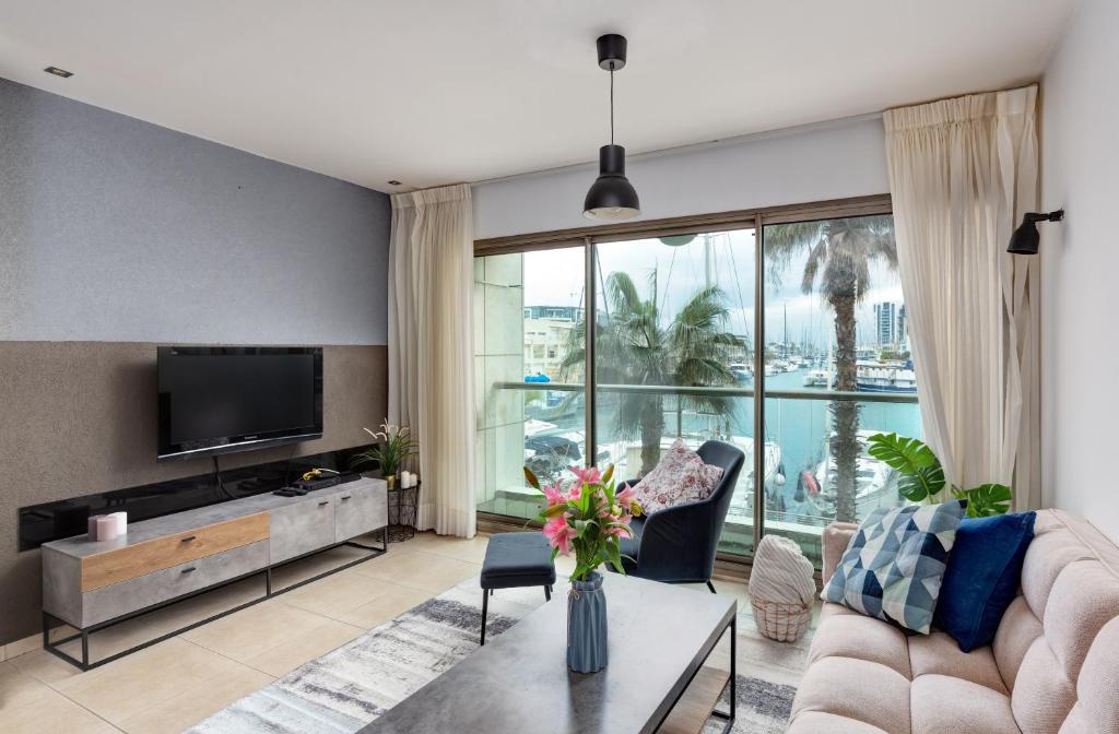 a living room with a couch and a tv at Marina View One Bedroom Dream Suite in Herzliya