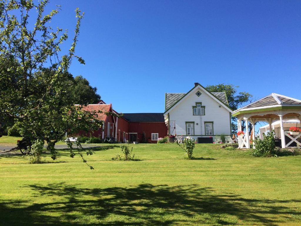 una gran casa blanca con cenador en un patio en Strømnes - Oldefars gjestehus Inderøy, en Straumen