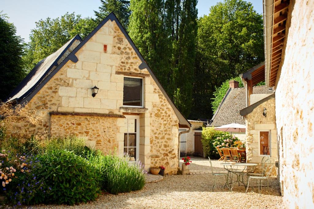 a stone house with a patio in a yard at Domaine de la Juranvillerie, gîte et chambres d'hôtes in Rigny-Ussé