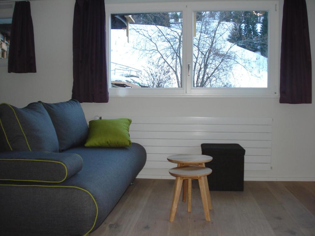 a living room with a blue couch and a window at Chalet Viola in Wengen
