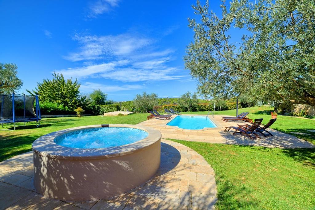 a swimming pool with a large tub in a yard at Apartment Villa Mare1 with pool, sea view and hydromassage in Banjole