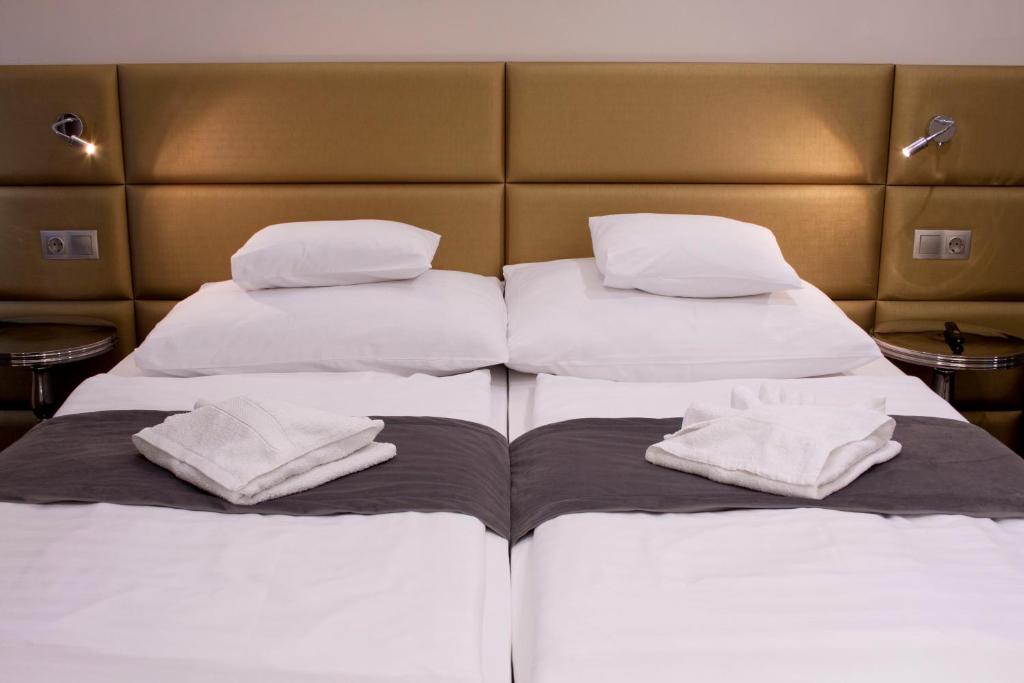 two beds in a room with white sheets and pillows at Relax Panzió in Győr