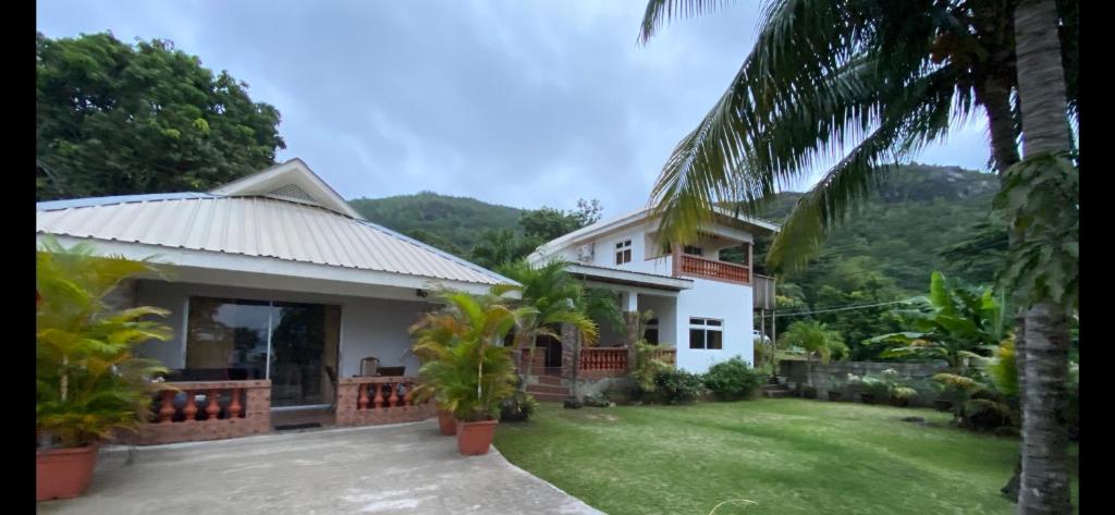 ein Haus mit einem grünen Garten und Palmen in der Unterkunft Villa Kass in Baie Sainte Anne