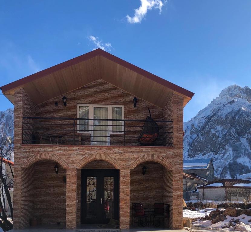 a brick house with a balcony on top of it at Cozy Place in Kazbegi in Stepantsminda