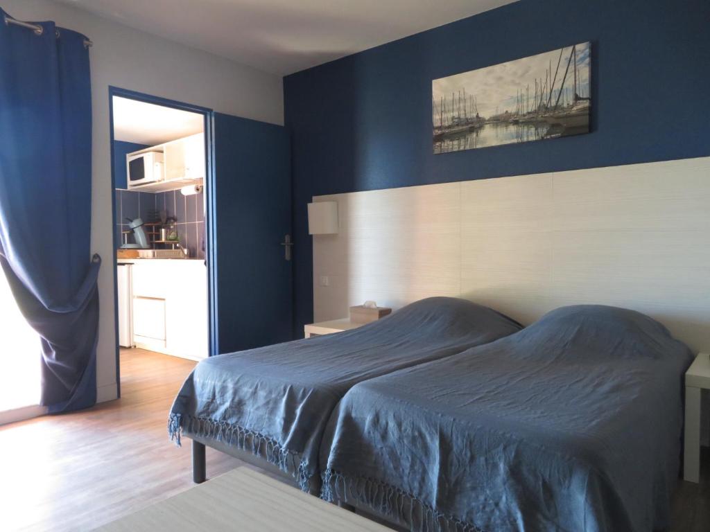 une chambre avec un lit avec un mur bleu dans l'établissement Appartement village 9 en résidence de vacances en Camargue, à Arles