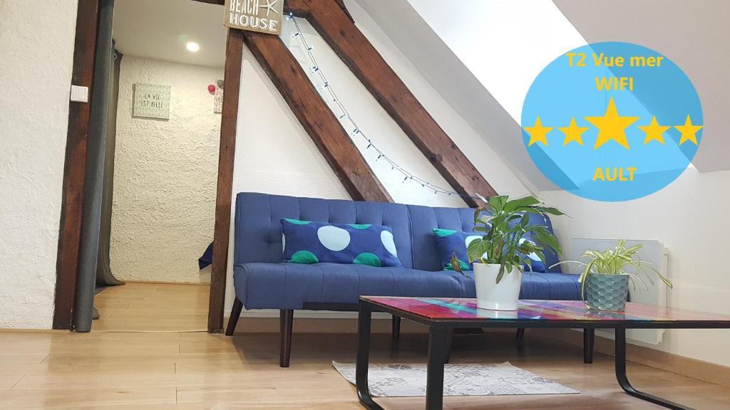 Appartement centre village vue mer - Relais Fleuri في أولت: أريكة زرقاء في غرفة المعيشة مع طاولة