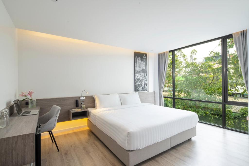 a bedroom with a bed and a desk and a large window at Amarin Hotel Rama 8 in Bangkok